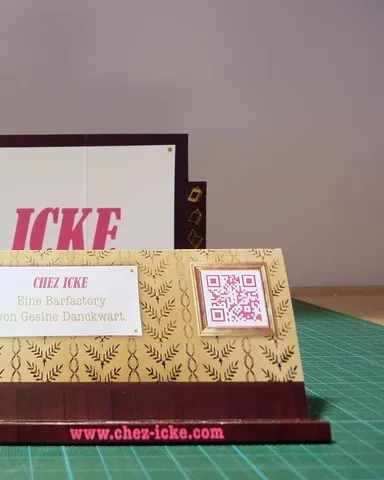 Chez-Icke-Visitenkarte mit QR-Code neben Smartphone mit mobiler Website