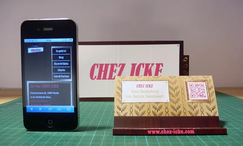 Chez-Icke-Visitenkarte mit QR-Code neben Smartphone mit mobiler Website