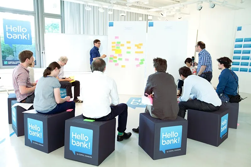 Teilnehmer des Workshops auf Hello bank Sitzwürfeln vor Pinnwand