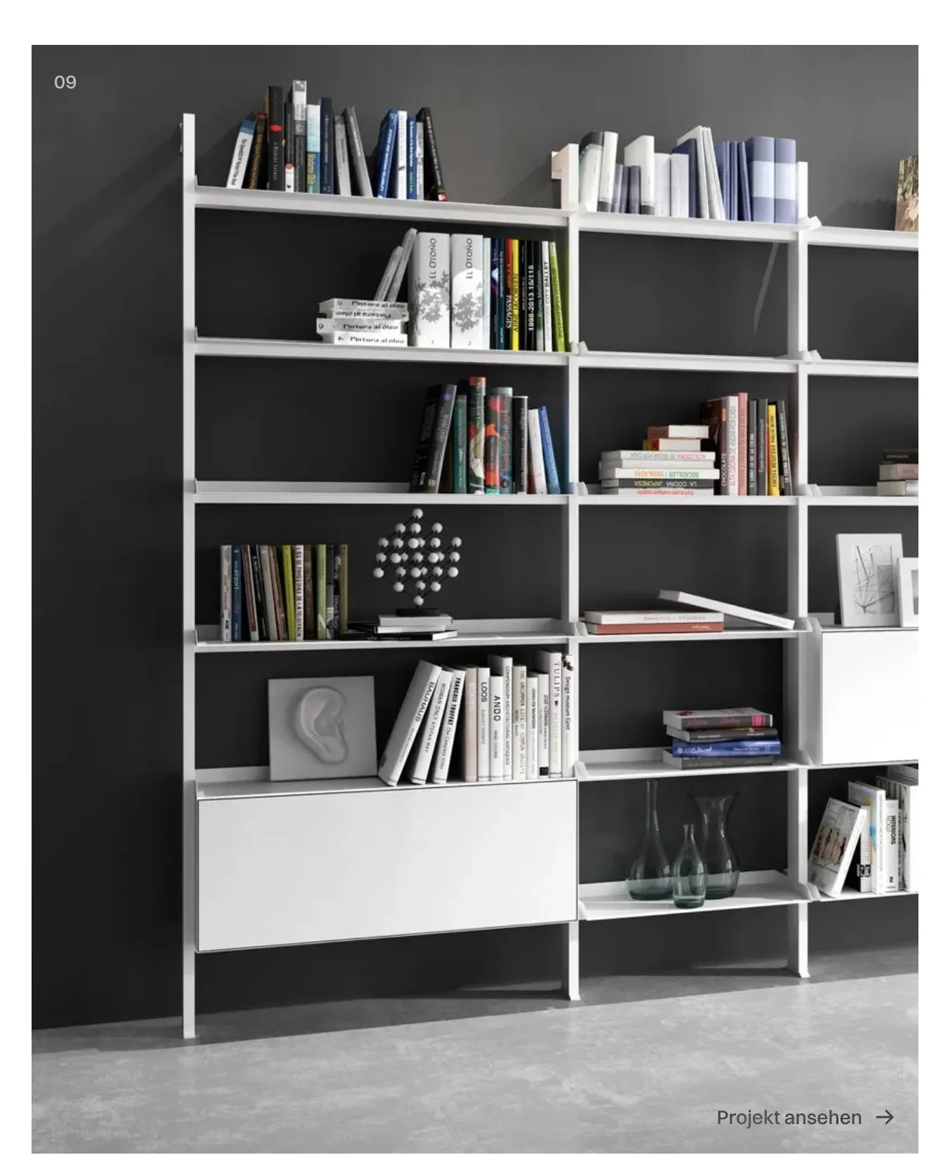 Weißes Wandregal SCALA mit Büchern, Vasen und Objekten vor dunkelgrauer Wand