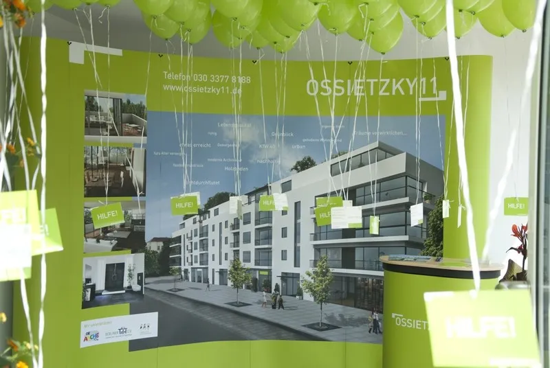 Showroom-Innenraum mit Projektplakat OSSIETZKY11 und grünen Ballons