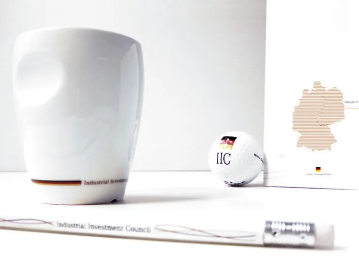 Weiße Kaffeetasse, Golfball und Stift mit IIC-Logo und Deutschlandkarte