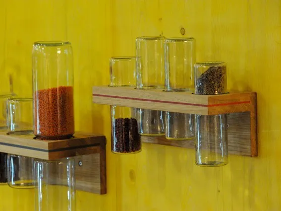 Zwei spicebar Regale an gelber Holzwand mit Gewürzen in Gläsern