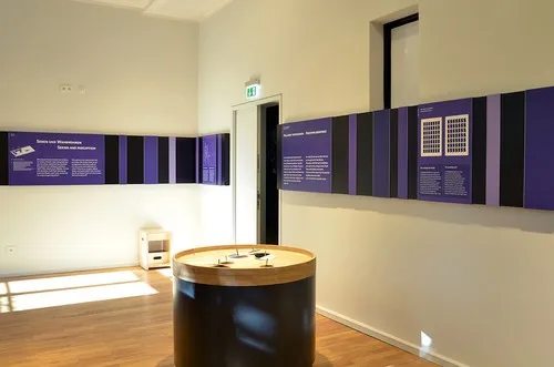 Heller Ausstellungsraum mit violettem Wandspektrum und rundem Exponatetisch