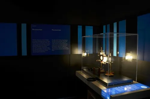 Exponat in Glasvitrine vor blauen Wandpaneelen im abgedunkelten Raum