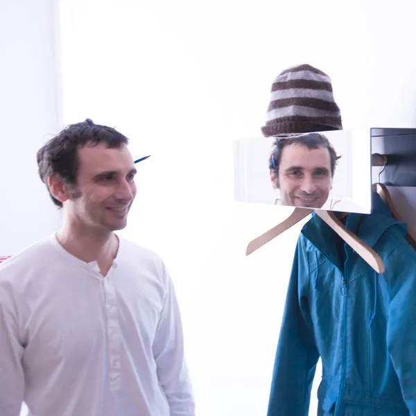 Spiegelfläche der Garderobe zeigt Gesicht und Mütze auf Bügel
