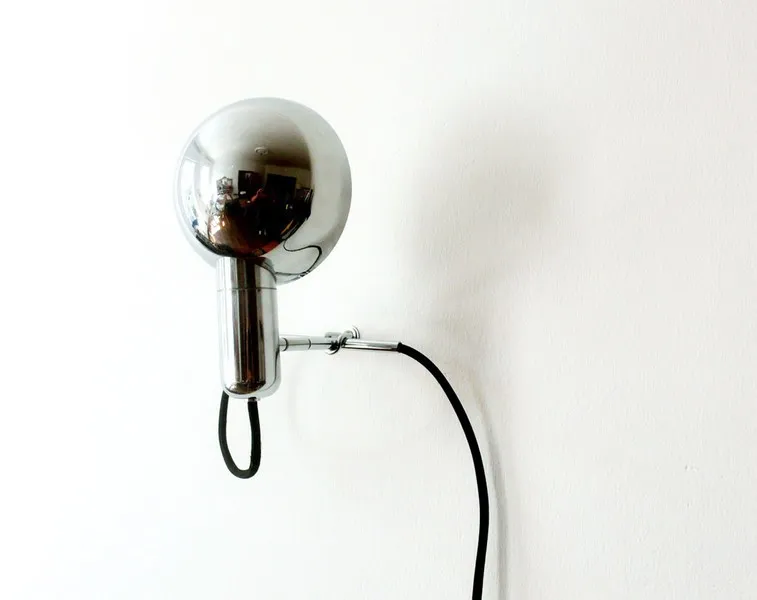 Verchromte re-flect Leuchte an der weißen Wand mit schwarzem Kabel