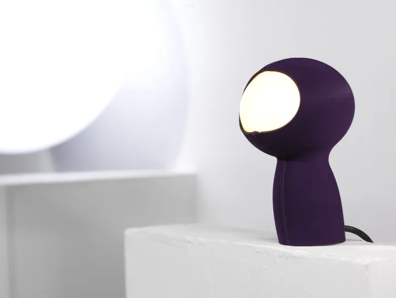 Violette MiM Leuchte auf weißem Podest mit schwarzem Kabel